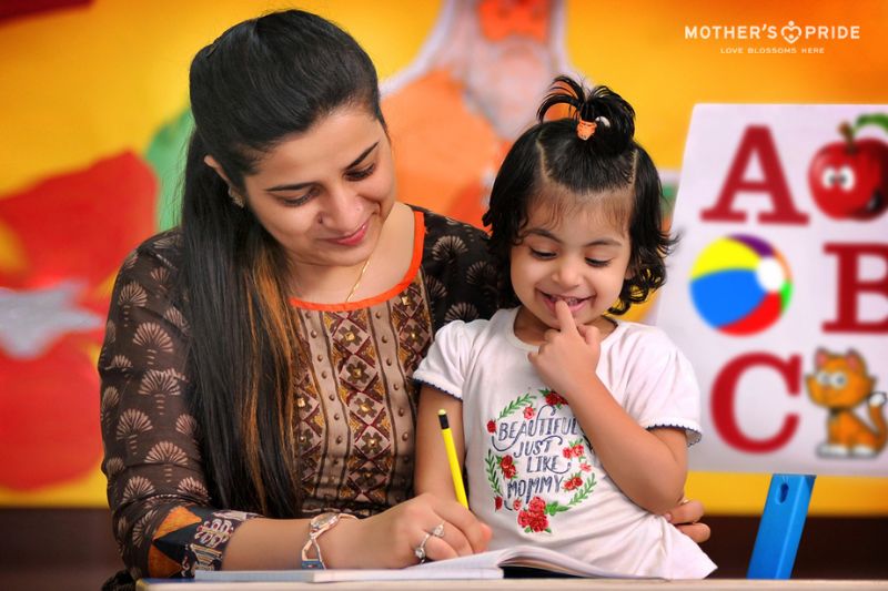 Caring teacher supporting a child during a creative drawing session at a preschool in Pataudi